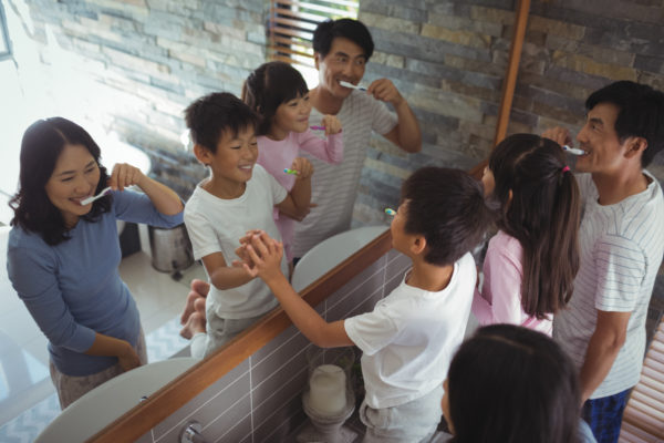 family brushing teeth together in mirror